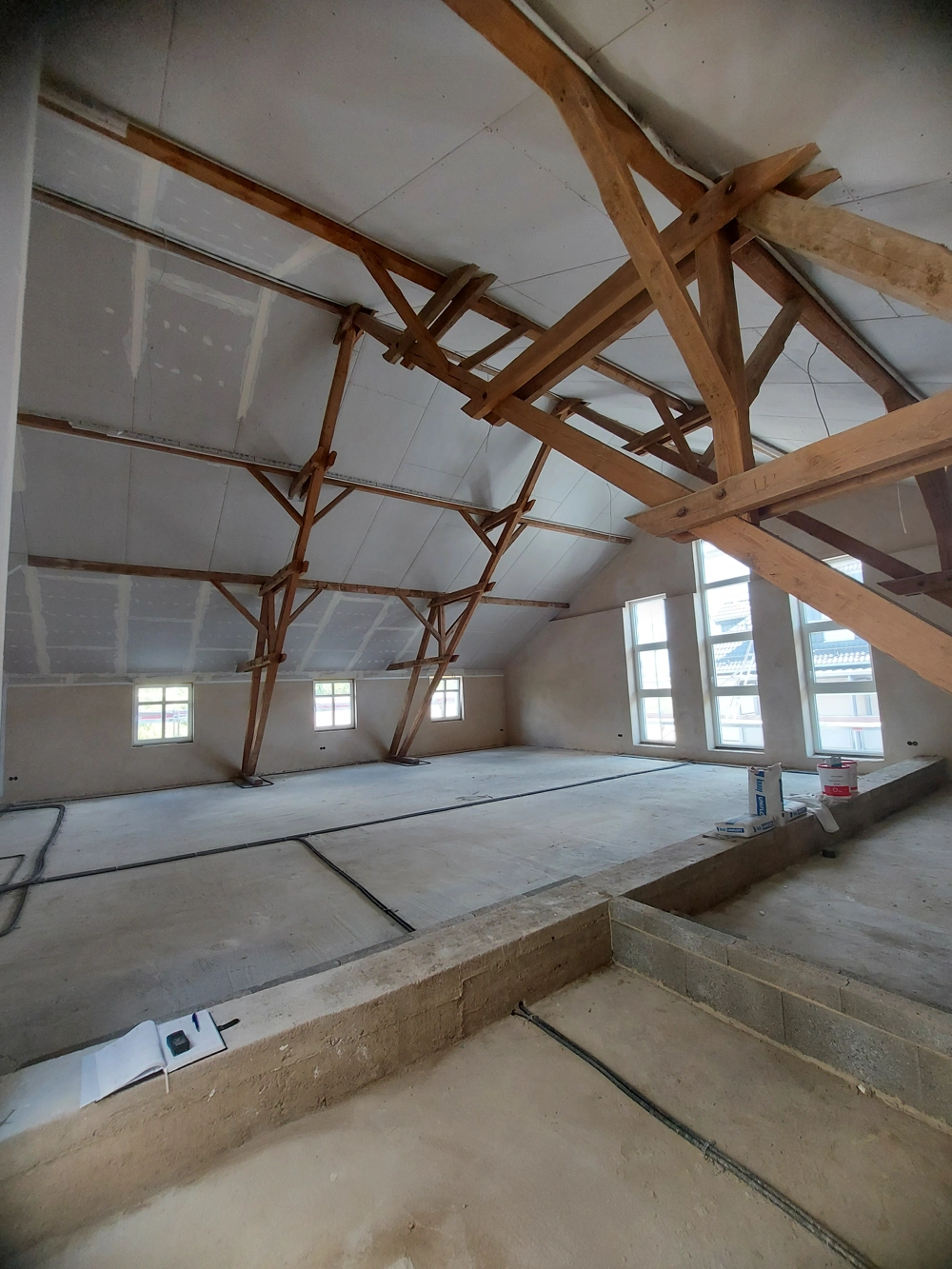 Freier Dachboden mit sichtbarem Holzdachstuhl, Gipskartonwänden und Elektroleitungen Dachbodenausbau