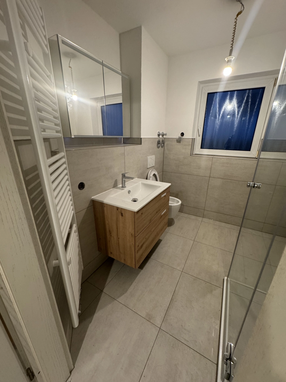 Modernes Badezimmer mit wandhängendem Waschtischunterschrank, Spiegel, WC und bodengleicher Dusche nach Badsanierung